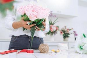 young women business owner florist making or Arranging Artificial flowers vest in her shop, craft and hand made concept photo