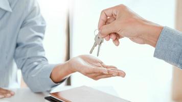 agente que entrega las llaves de la casa al cliente después de firmar el acuerdo de propiedad, en relación con la oferta de préstamo hipotecario y el seguro de la casa.