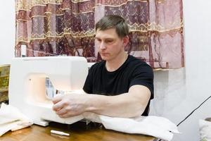 a man sews on a sewing machine photo
