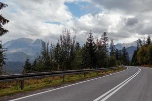 paisaje otoñal de invierno, montaña que se desvanece en el día nublado de niebla y una carretera asfaltada foto