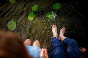 pareja chapoteando sus pies en el agua al atardecer foto