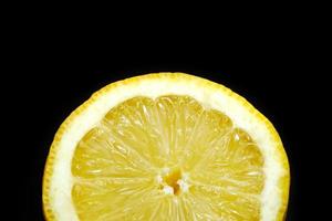 slice of yellow ripe lemon isolated on a black background. selective focus photo