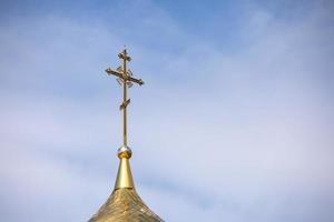 la cúpula dorada y la cruz de la iglesia ortodoxa contra el cielo azul y las nubes. foto