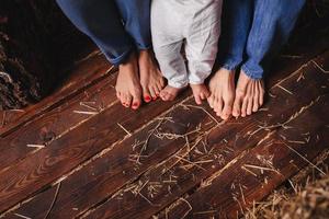 pies descalzos de miembros de la familia-madre, padre e hijo. suelo de madera foto