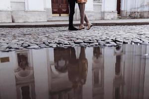 cropped photo of Happy young stylish couple, enjoying their hugging in old road in city street with ancient building on the background. after rain. selective focus