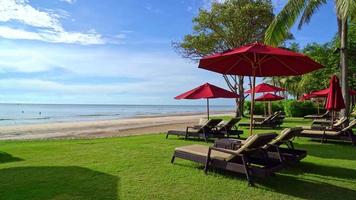 sombrilla roja y silla de playa con fondo de playa de mar y cielo azul y luz solar