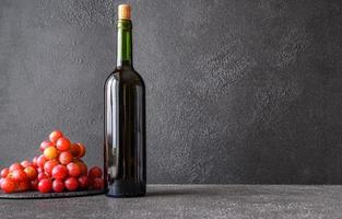 botella de vino con racimo de uvas foto