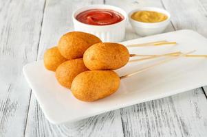 Corn dogs on white serving plate photo