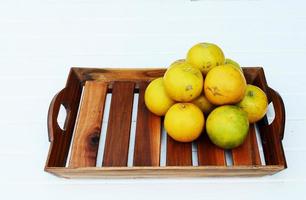 Orange fruits in wooden basket on white table backgrounds photo