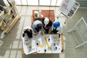 View From Above of Architect and Engineer Team Looking at Blue Print of Building in Meeting photo