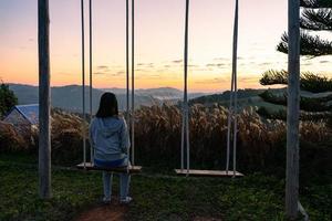 vista lateral de una mujer madura sentada en una silla giratoria y mirando el amanecer durante las vacaciones foto