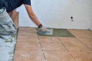 Laying tiles on the floor of the room on the construction site photo