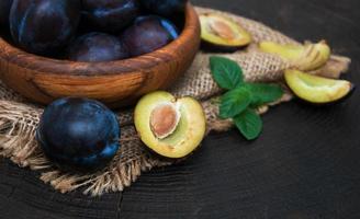 Bowl with  plums with green leaves photo