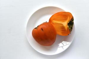 rodajas de caqui diospirosis en un plato blanco foto