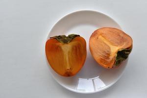 Diospyros persimmon slices on a white plate photo