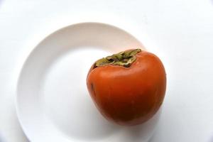 Ripe persimmon fruit Diospyros on a white plate photo