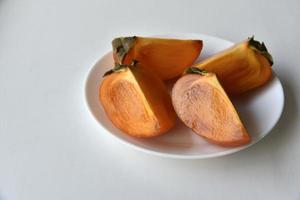 Diospyros persimmon slices on a white plate photo