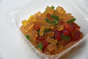 Plastic box with marmalade bears on a white background photo