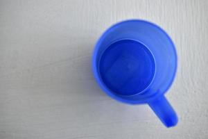 Taza de plástico azul sobre un fondo blanco. foto