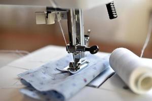nueva máquina de coser blanca con hilos en casa foto