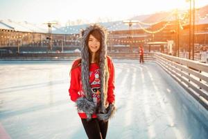 young happy woman in hat skating on ice on the street photo