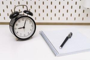 notebook with a black alarm clock and a pen on a white background. photo