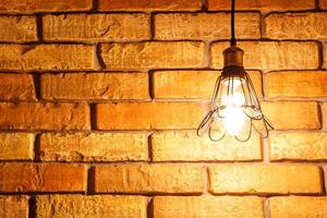 Luminous light bulb in the loft style on the background of a brick wall, copy space photo