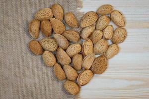 Almonds in the shell in the form of heart on a wooden background, view from the top photo