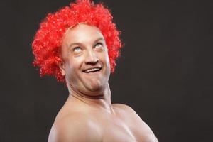 Portrait of a man in a bright red curly wig, funny facial expressions, on the background photo