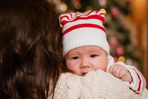 Pretty young woman with one-year-old baby in her arms, against background photo