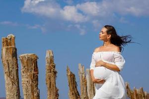beautiful young pregnant woman standing in nature on salt lake photo