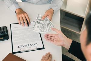 Money in the hands of businessmen who are submitting to entrepreneurs to force the signing of contract documents about corruption concept. photo