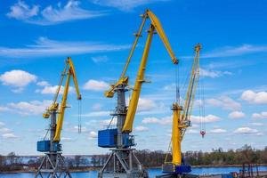 Marine loading cranes of yellow color on a background of blue sky with clouds. photo