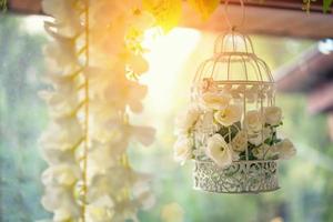 hermosa decoración, jaula blanca con flores colgando de la ventana foto