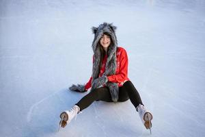 A young woman is sitting on the ice and smiling. photo