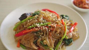 japchae of geroerbakte Koreaanse vermicelli noedels met groenten en varkensvlees gegarneerd met witte sesam - Koreaanse traditionele voedselstijl video