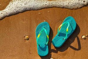 las chanclas de las mujeres se paran en la playa en la arena, concepto de vacaciones foto