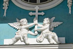 two angels holding a cross , stucco on the wall of the temple photo