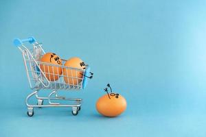 Store toy cart with brown eggs, funny faces painted on the shell. On a blue background.  Concept photo