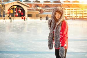 young happy woman in hat skating on ice on the street photo