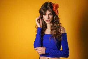 portrait of a beautiful young woman on a yellow background, beautiful flower in her hair, delicate natural make-up photo