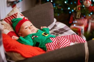 hermoso niño de medio año yace sobre almohadas y sonríe con un traje rojo-verde foto