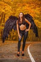 beautiful woman with black wings in autumn forest photo