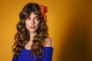 portrait of a beautiful young woman on a yellow background, beautiful flower in her hair, delicate natural make-up photo