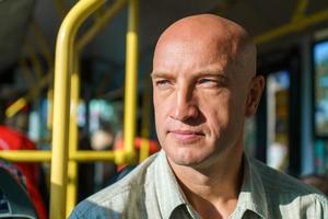 Travel safely by public transport. A young bald man looks through bus window. photo