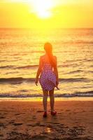 silhouette at sunset girl on the beach, evening walks on the coast photo