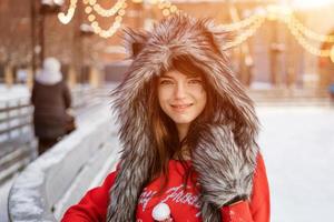 mujer joven feliz en un sombrero de lobo en invierno en la pista de hielo foto