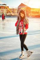 young happy woman in hat skating on ice on the street photo