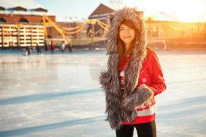 young happy woman in hat skating on ice on the street photo
