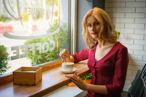 hermosa mujer sentada junto a la ventana en un café tomando café. foto